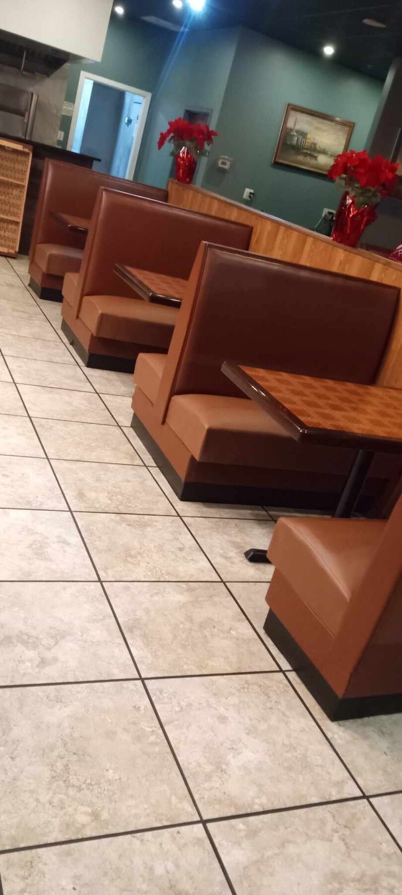 Rows of booth seating in rust and brown vinyl installed along a restaurant dining room