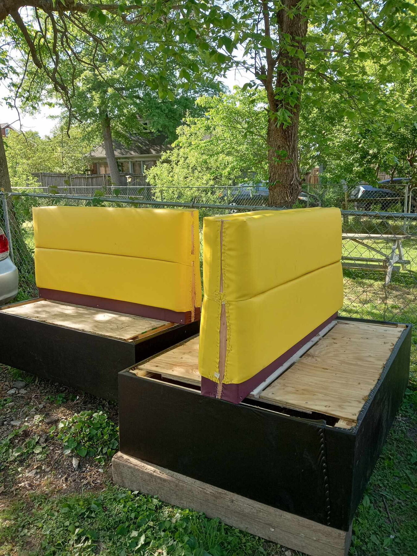 Two booth units with sewn yellow backs on maroon bases, staged outdoors and ready for delivery