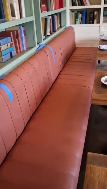 Terracotta channel-tufted leather banquette, installed in a library dining room