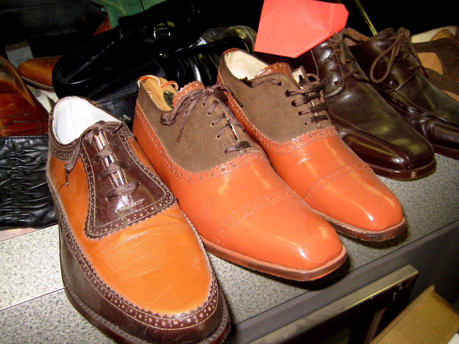Shelf of finished men's shoes, two-tone saddle oxfords at the front