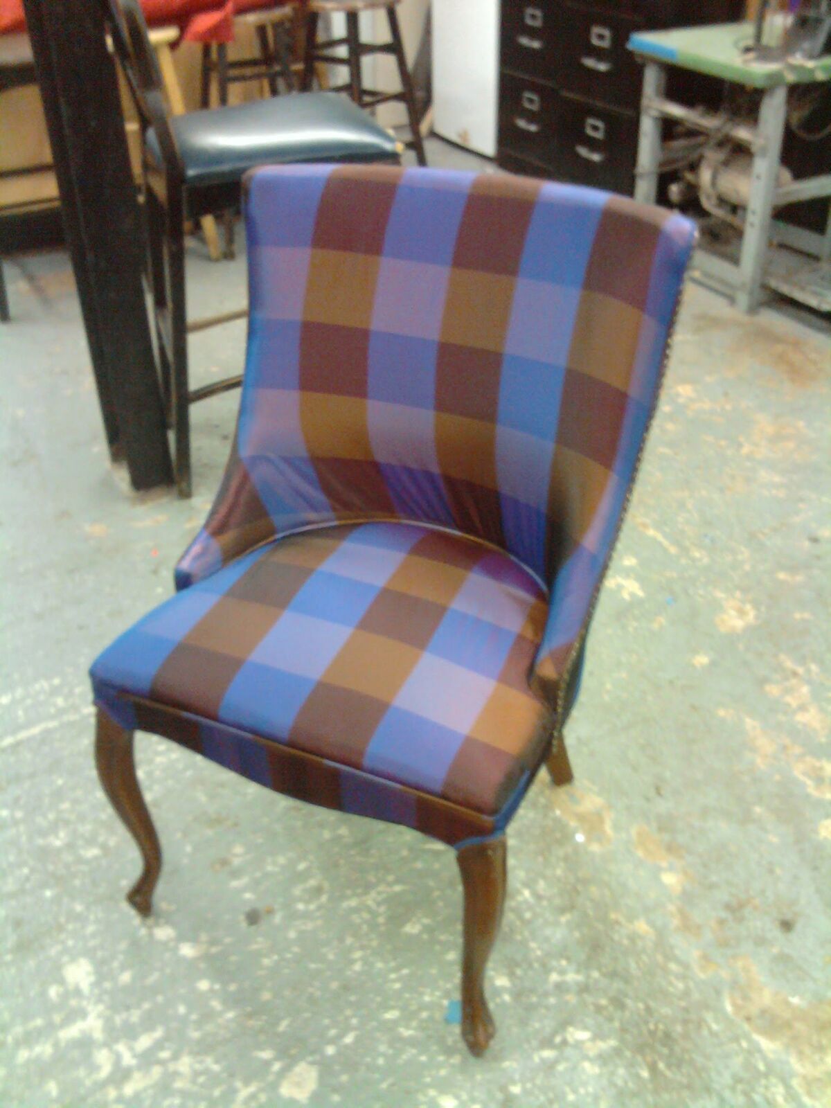 The same side chair finished in blue-and-brown checked fabric with nailhead trim