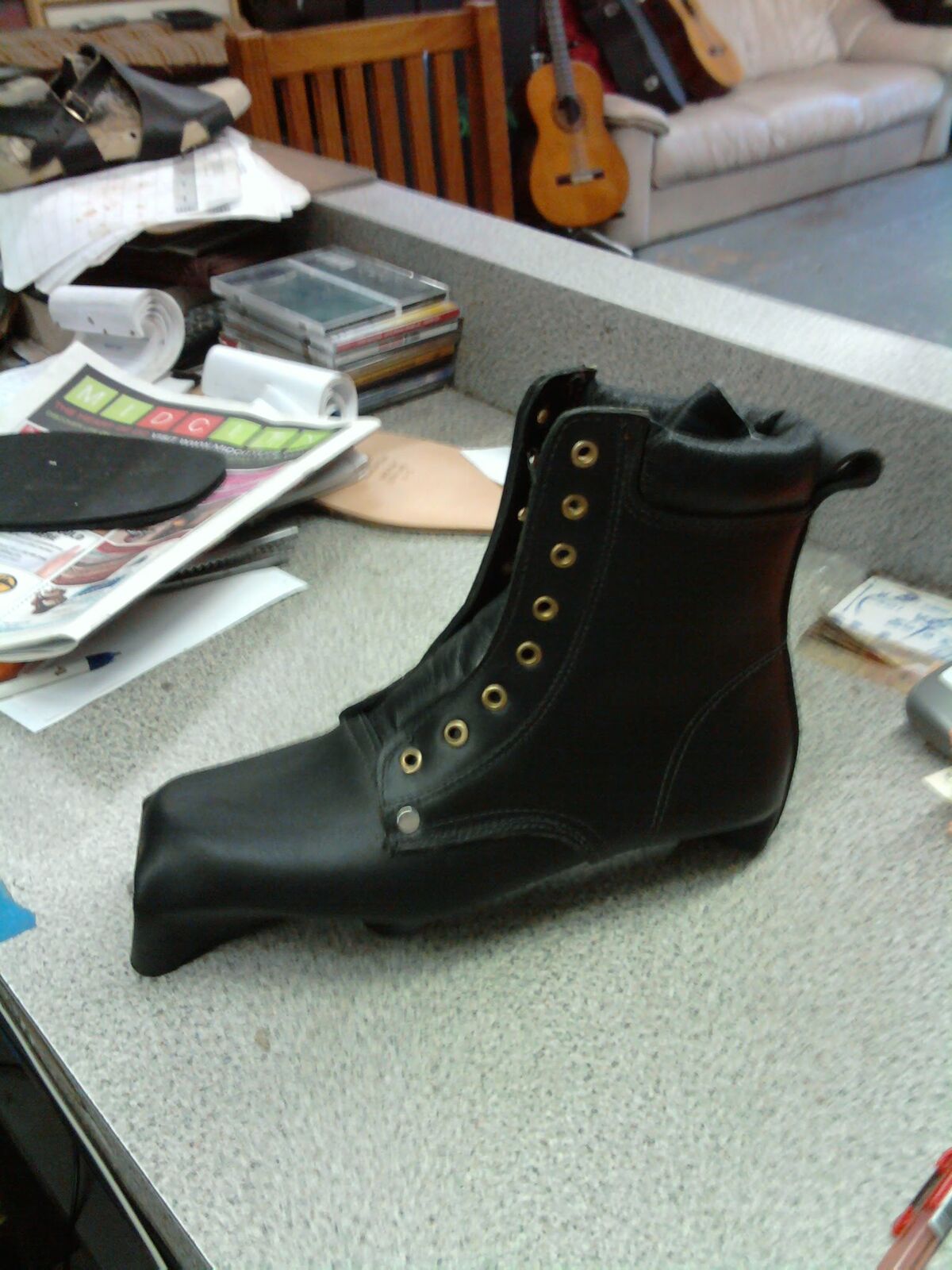 Black leather lace-up work boot in progress, eyelets set and laces still to come